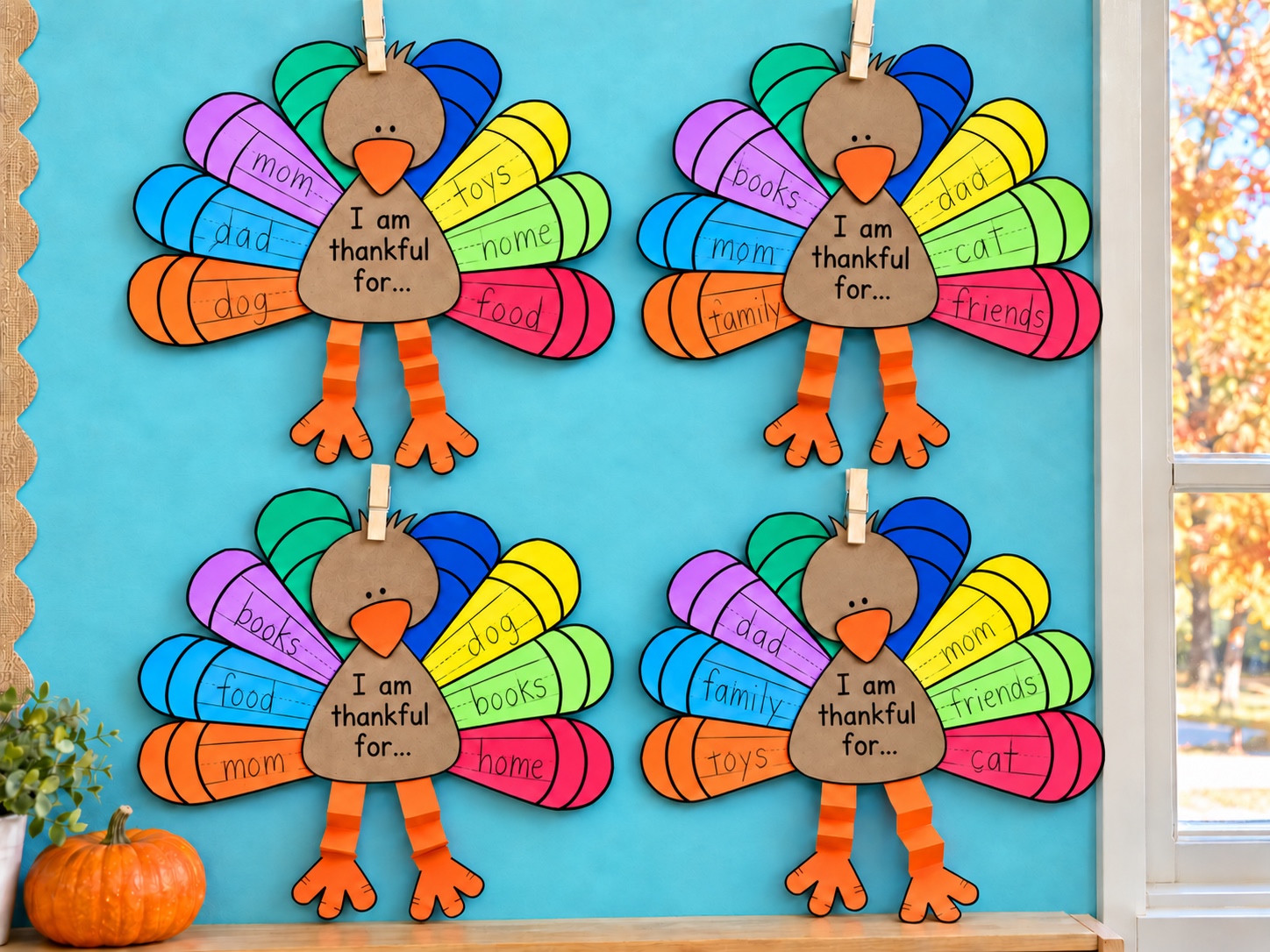Four Thankful Turkey crafts with colorful writing feathers displayed on a turquoise bulletin board.